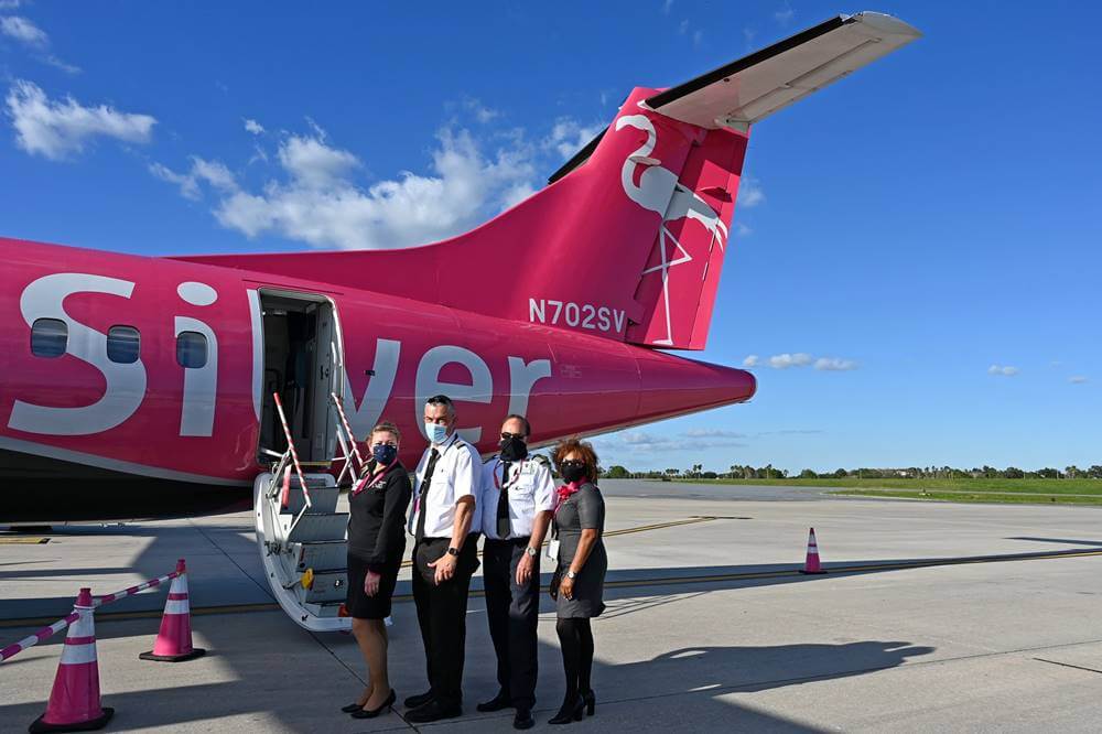 silver airways flight attendants with pilots behind airplane