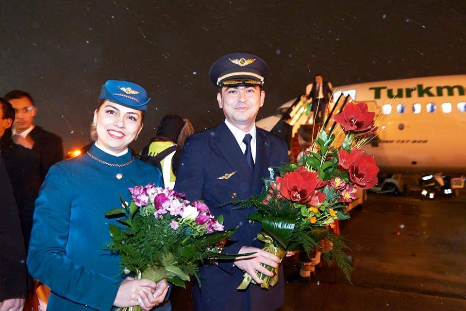 Turkmenistan Airlines male and female flight attendant flowers